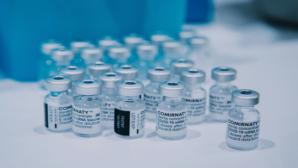 Multiple Bottles of COVID Vaccine sitting on a white table.